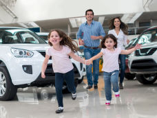 Couple with their two kids holding hands and running in EV showroom