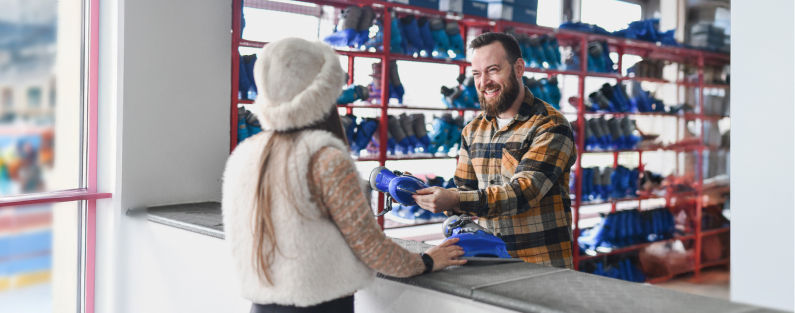 Man renting ice skates to young woman