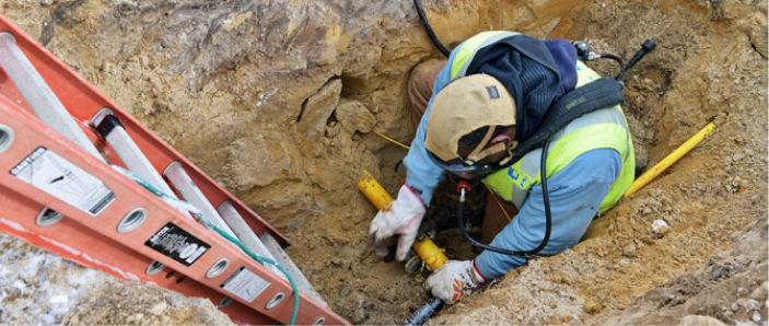 A DTE service technician installing a natural gas pipeline in the ground.