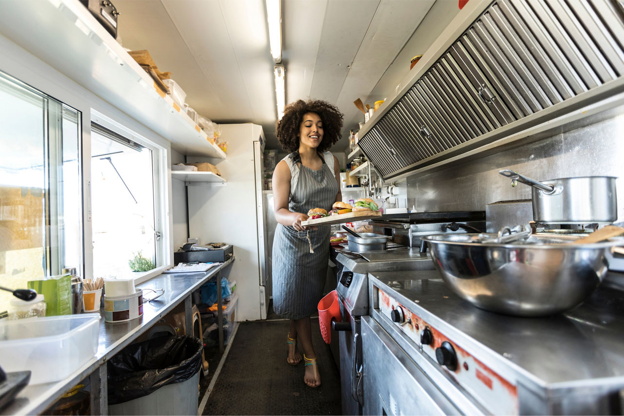 woman preparing food in a food truck type setting