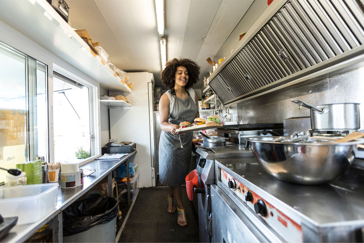 woman preparing food in a food truck type setting