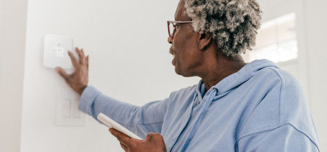 Woman is adjusting the thermostat in the kitchen.