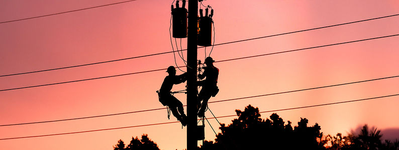 Linemen working on lines with sunset in background
