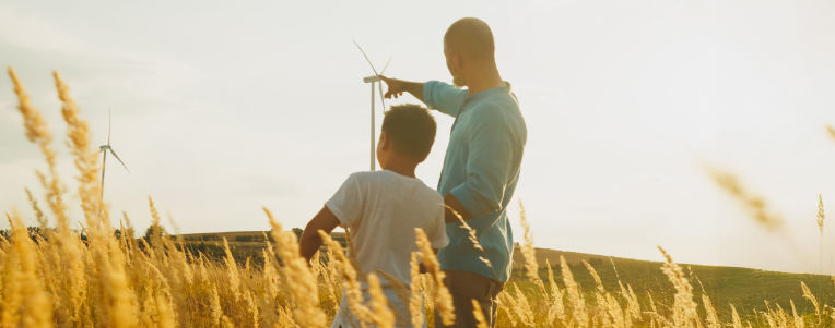 Adult man and child in a field of wheat looking into the sunset