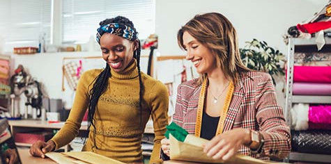 Two women discussing plans about their fabric business.