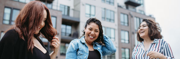 three young woman smiling in front of an apartment building