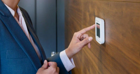 Woman is adjusting the thermostat in the workplace.