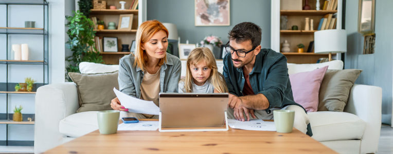 Family sitting together at a table looking at a laptop