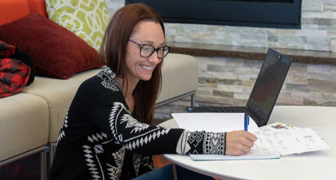 A woman taking notes while working on her computer