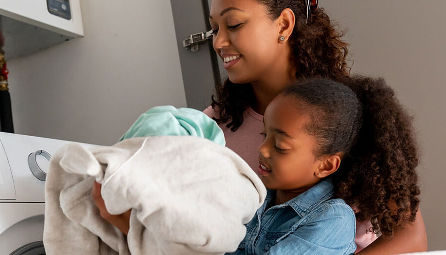 Mom and daughter doing laundry and smiling