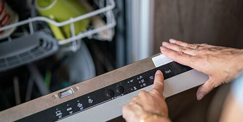 Close up of hands scheduling a dishwasher