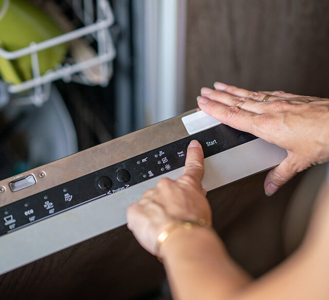 Close up of hands scheduling a dishwasher