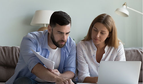 Couple sitting in a living room reviewing bills together.