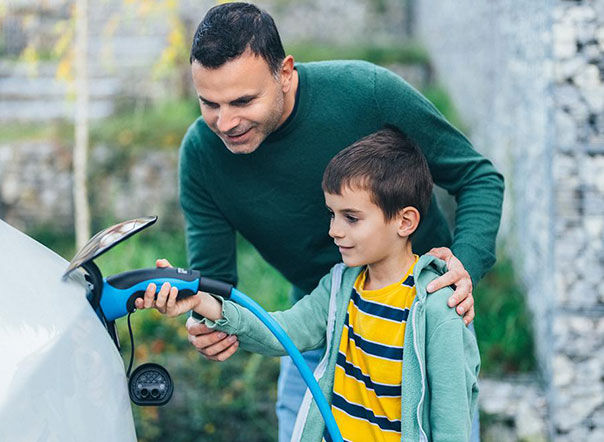 Dan and son charging electric vehicle outdoors