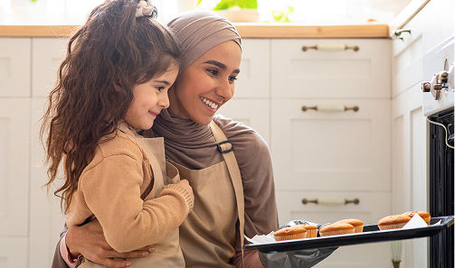 Mom and daughter putting cookies in the oven