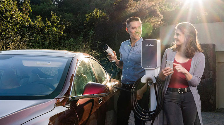 Couple charging electric vehicle and looking at each other smiling