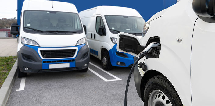Closeup of a van with a Level 2 Charger and two other vans in the background.