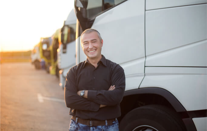 Man smiling in front of a row of electric vehicle trucks