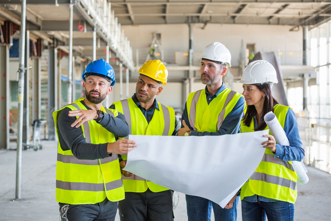 group of DTE employees looking over blueprint inside a building in construction