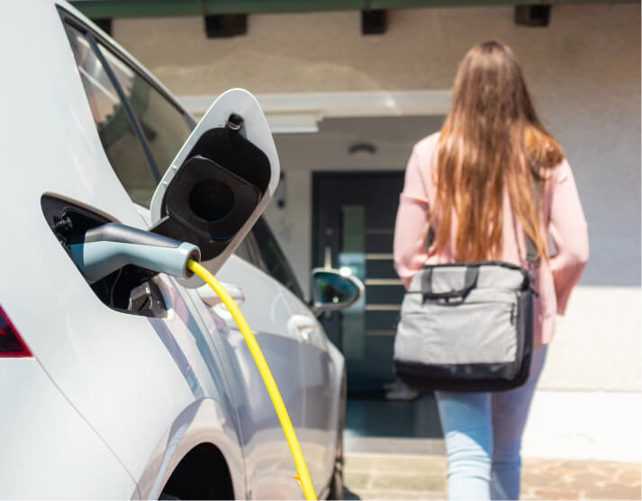 Electric vehicle charging and woman walking towards her home