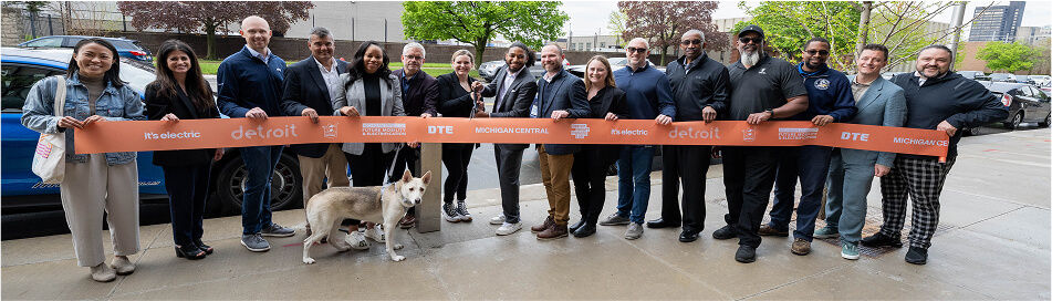Several people holding an orange ribbon with company logos