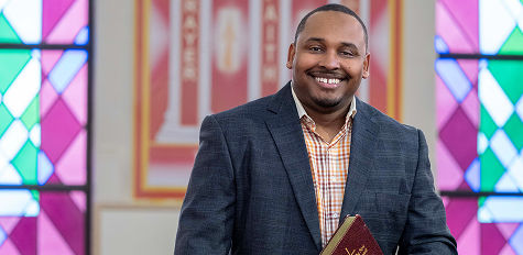 A pastor smiling at camera inside a church.