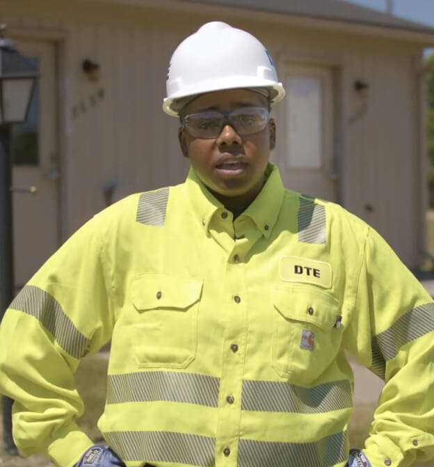 DTE employee looking at camera and wearing a safety yellow top and hard white had