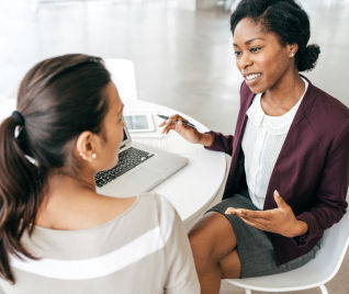 DTE energy advisor discussing with another woman around a small round table and laptop