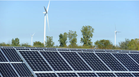 Roof top solar panes and wind turbines in the background