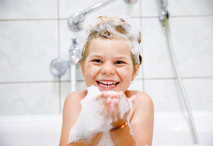 Little boy taking a bubble bath and smiling