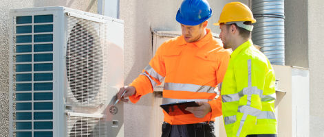 2 men looking air vent on a building roof