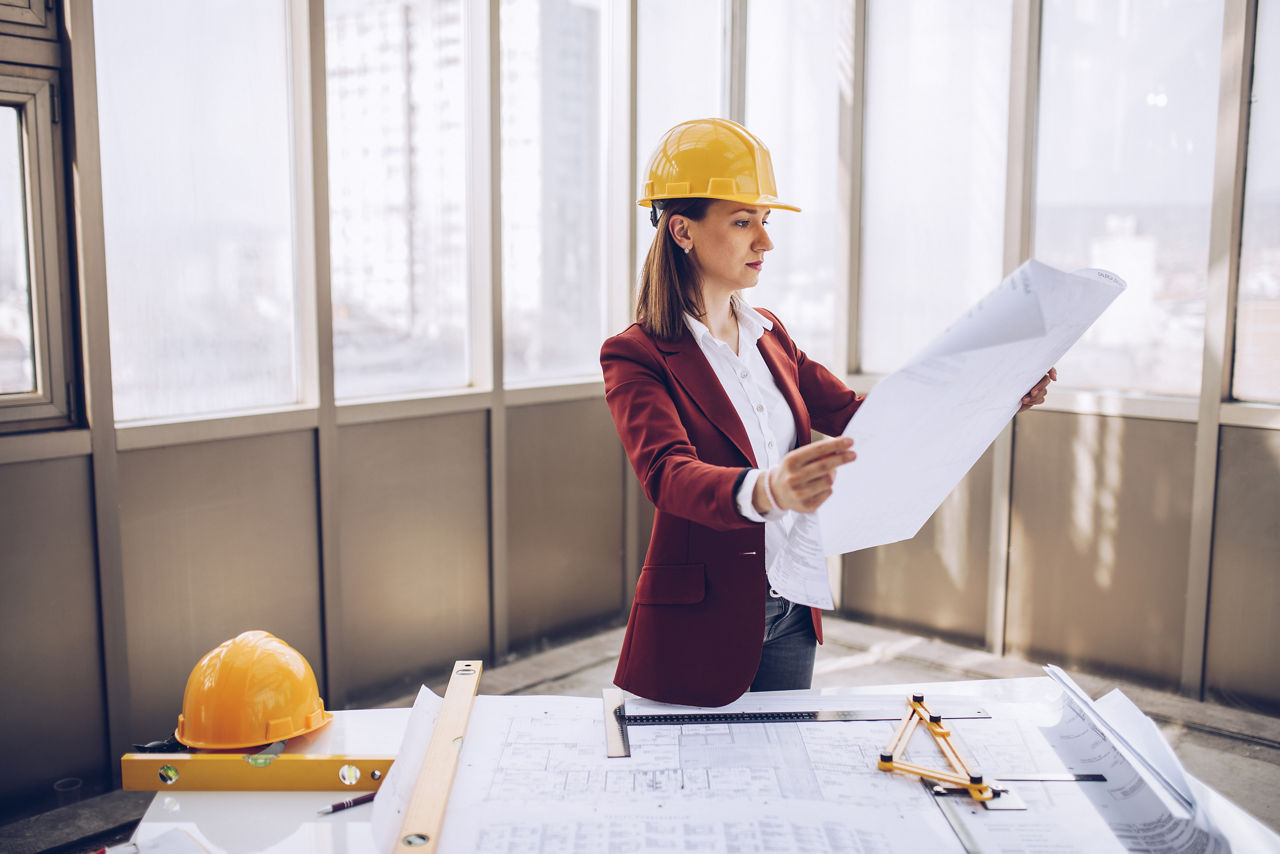 Woman with a hard hat reviewing plan in a new construction room