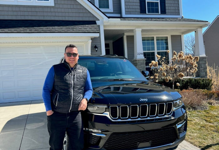 Man standing in front of his black Jeep Grand Cherokee 4xe SUV on his driveway