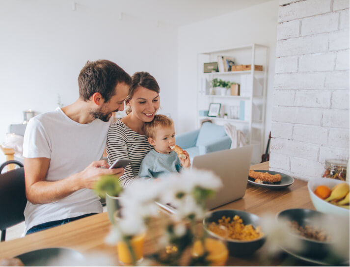 Family sitting in the kitchen with laptop