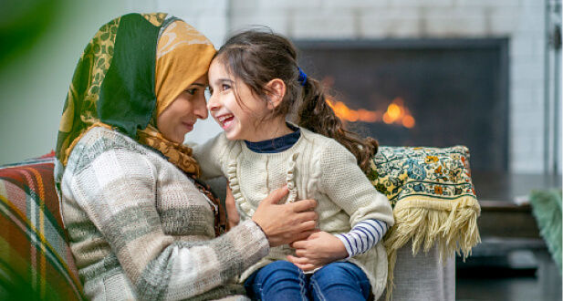 Mom and daughter sitting in living room and smiling with a fireplace in the background