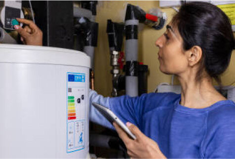 Woman adjusting a water heater while holding a tablet