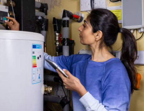 Woman adjusting a water heater while holding a tablet