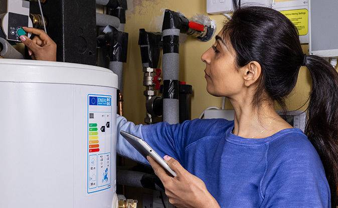 Cuple smiling while drying the dishes and a smart thermostat in the background