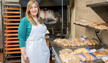 Woman smiling at the camera in front of baked goods