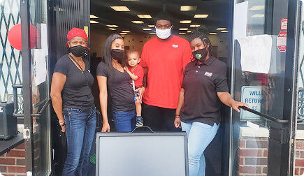 Family in front of a store looking at camera and smiling.