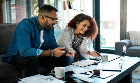 Couple sitting on a desk looking at bill on a laptop