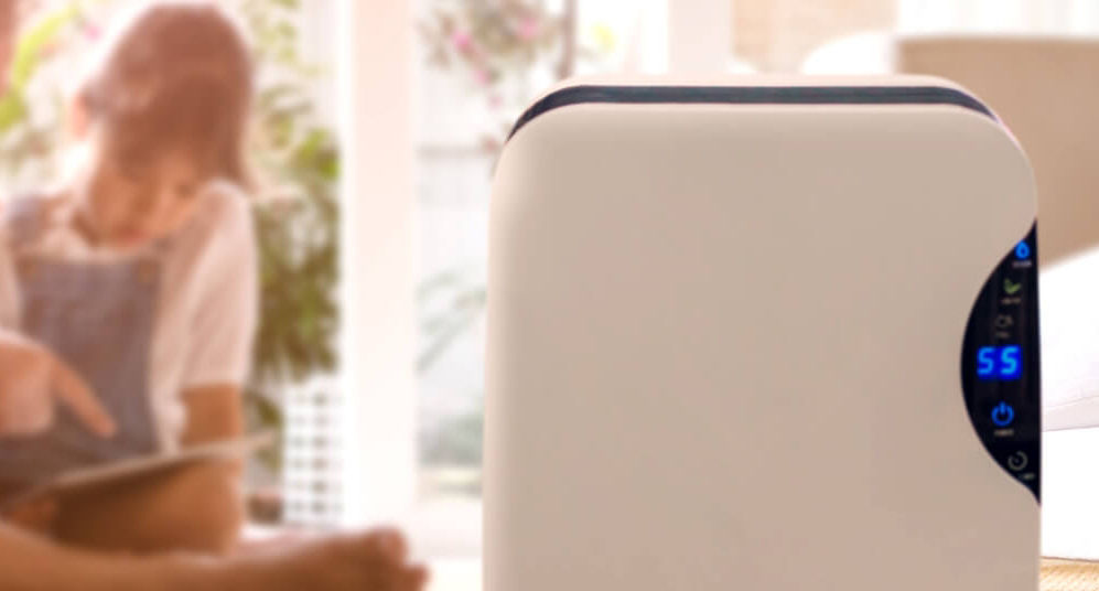 Young girl typing on tablet with a dehumidifier in front of her