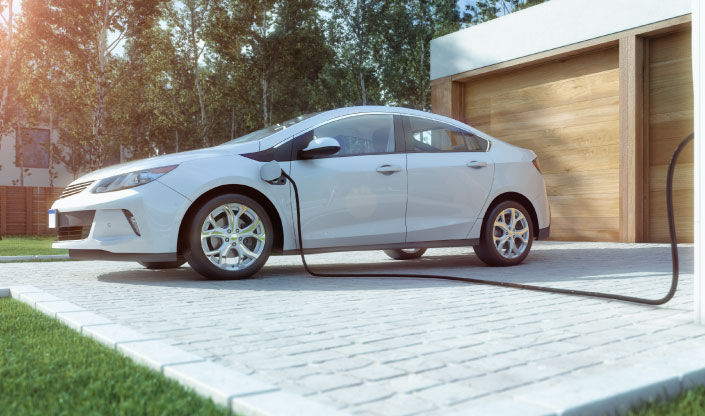 White electric vehicle charging in front of a garage