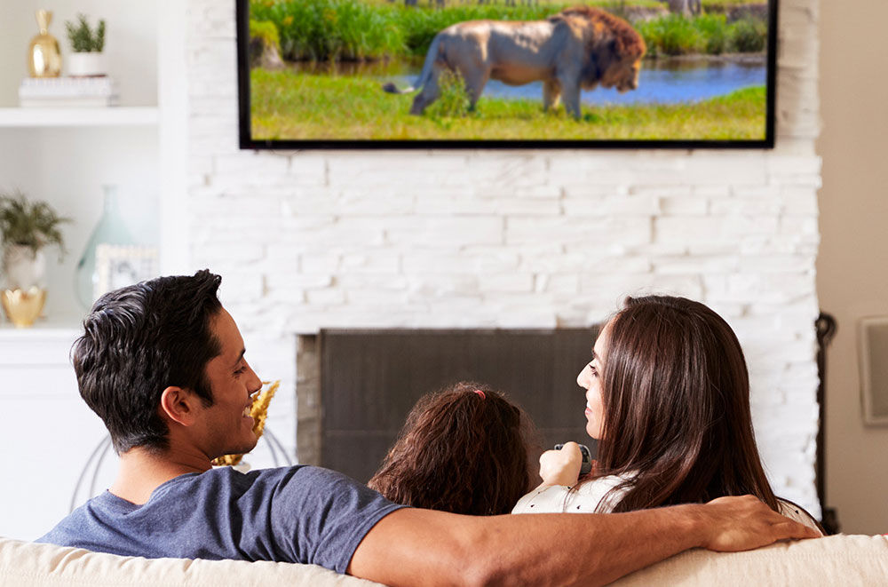 Family sitting in their livingroom watching TV