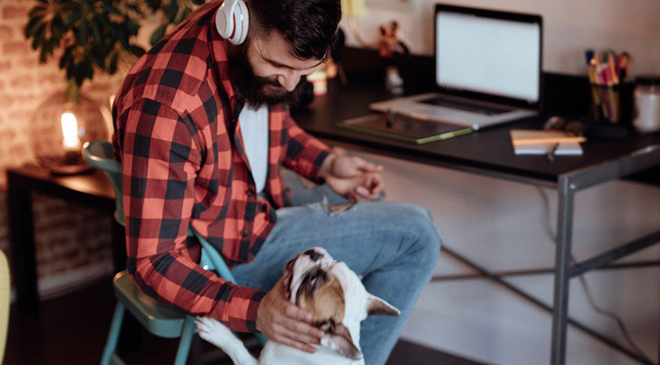 Man sitting in front of desk and petting his dog 