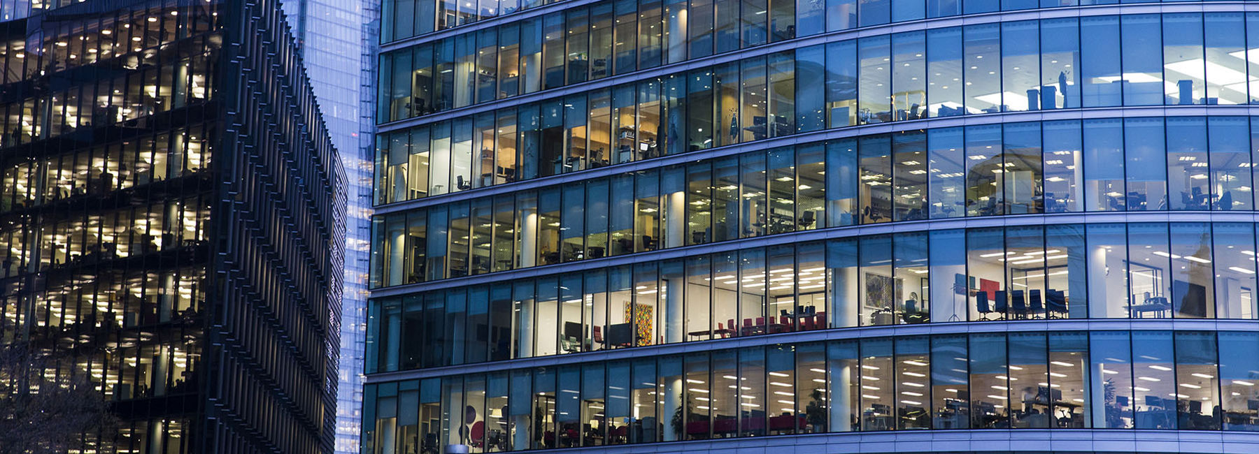 Blue-toned office building windows in business district in early morning, Google Cloud in banking | DXC Technology