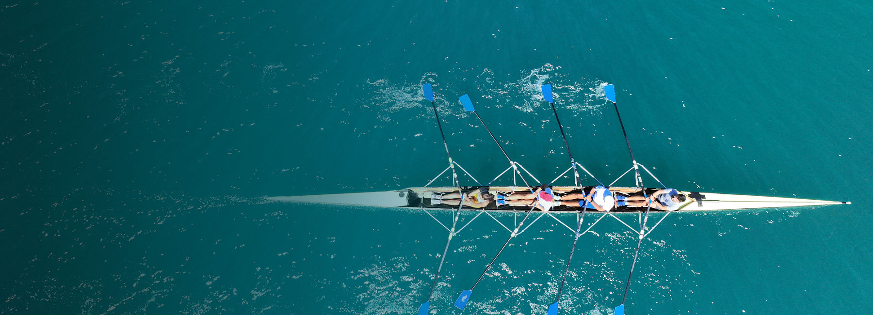 Aerial view of four rowers in a sport boat on emerald water | DXC Technology Campaign 