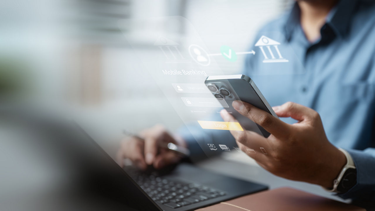 Person working with laptop and mobile representing Forensic & Financial Crime, Finance & Risk Advisory | DXC Technology