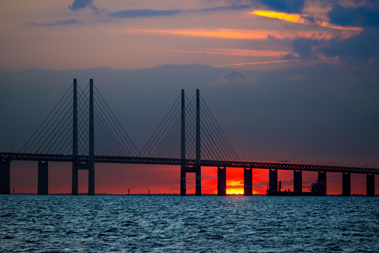 The landmark Øresund Bridge against a dark blue orange and red sky, Cloud & Infrastructure| DXC Technology