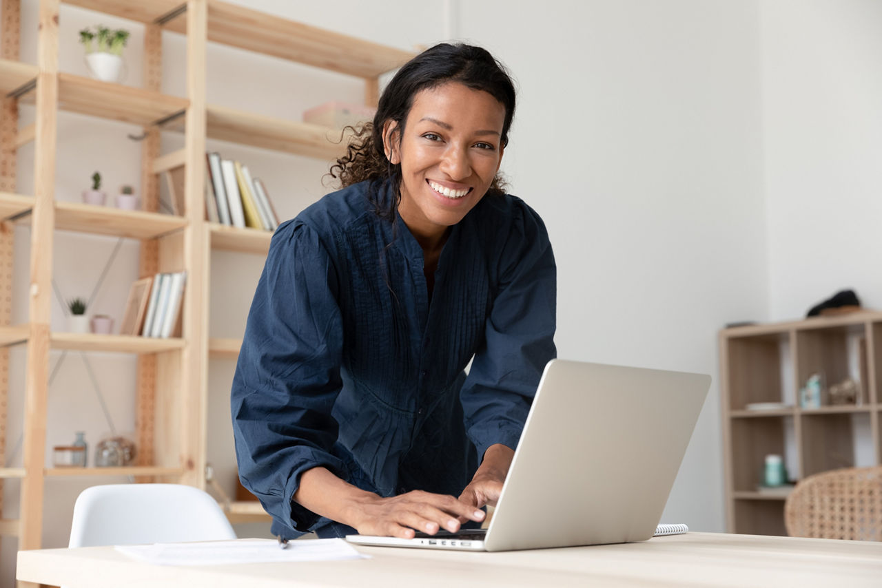 Woman standing at laptop and smiling, Site Support | DXC Technology